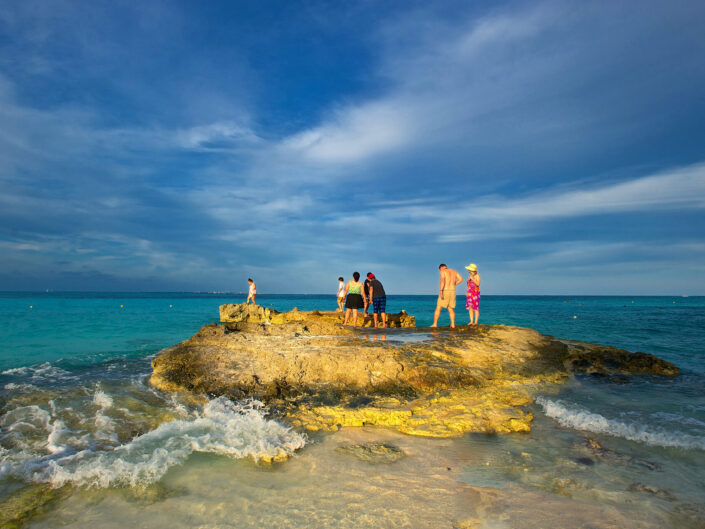 Tourists on Rock in Caribbean Sea at Golden Hour.